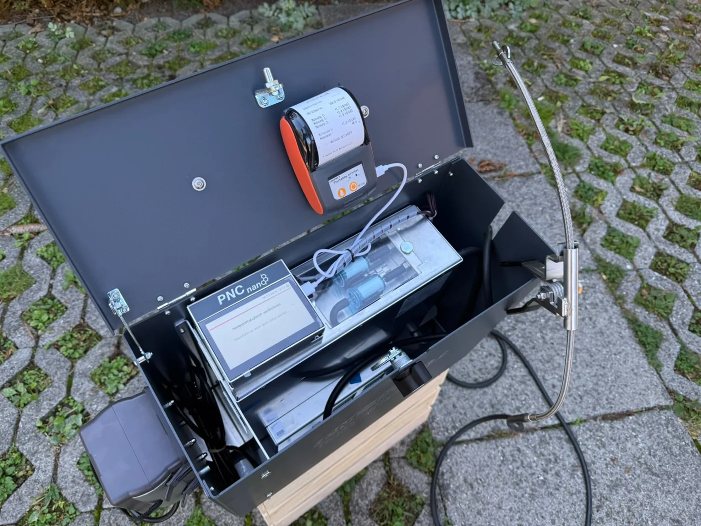 PNC-nano mit Sonde und Protokolldrucker Geöffnetes PNC-nano mit Abgassonde und Protokolldrucker vor Ort